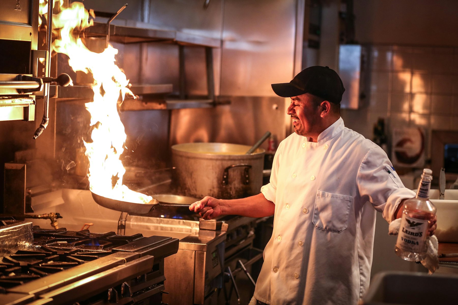 A cook flames a pan on the line during dinner service