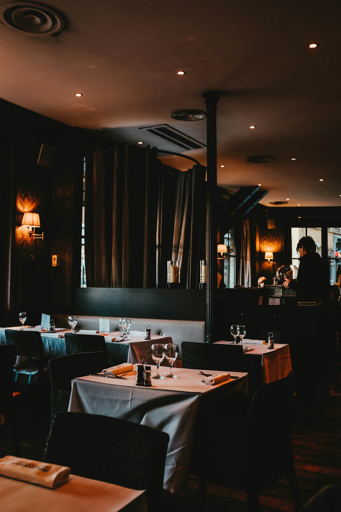 The Marrow and Sage dining room at night, white-clothed tables under low light